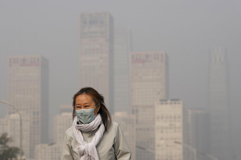Seorang wanita mengenakan masker untuk melindungi diri dari COVID 19 berjalan di depan gedung perkantoran di Kawasan Pusat Bisnis yang diselimuti kabut polusi di Beijing Kamis 18 November 2021 Beijing menerapkan kebijakan pencegahan dan pengendalian Covid 19 dengan memperketat impor Ilustrasi
