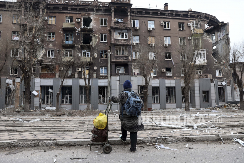 Seorang penduduk setempat melihat bangunan apartemen yang rusak akibat pertempuran sengit di dekat Pabrik Metalurgi Illich Iron Steel Works perusahaan metalurgi terbesar kedua di Ukraina di daerah yang dikendalikan oleh pasukan separatis yang didukung Rusia di Mariupol Ukraina Sabtu 16 April 2022