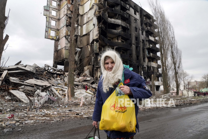 Seorang wanita tua berjalan di dekat gedung apartemen yang hancur dalam serangan Rusia di Borodyanka Ukraina Rabu 6 April 2022
