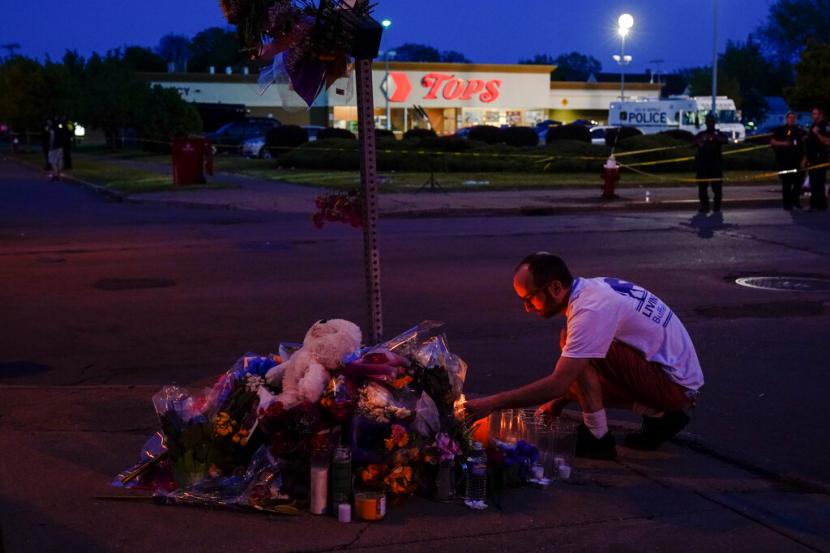 Seseorang memberikan penghormatan di luar lokasi penembakan di sebuah supermarket di Buffalo New York Ahad 15 Mei 2022
