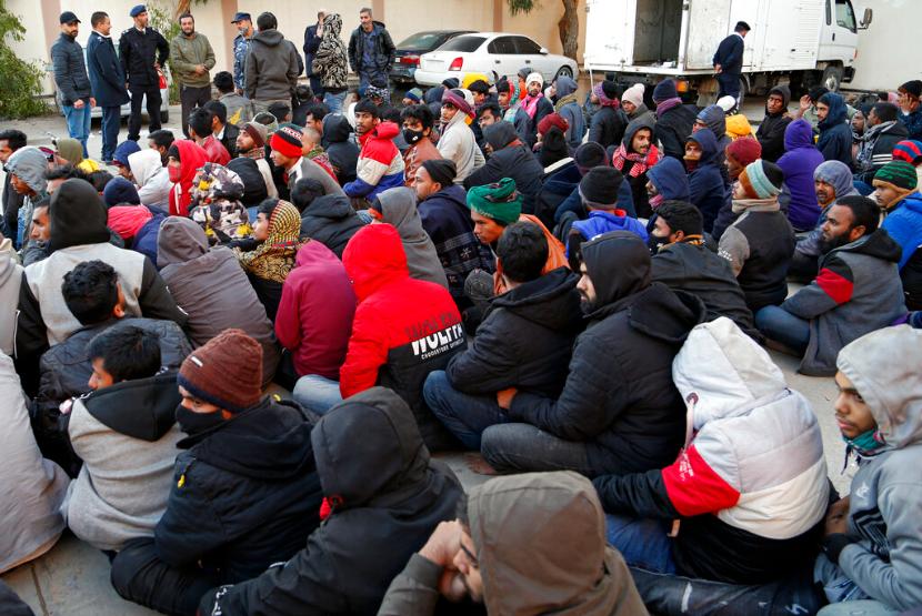Para migran yang ditahan duduk di depan pasukan keamanan setelah dikembalikan ke Libya menyusul upaya untuk menyeberangi Laut Mediterania di Misrata Libya Minggu 24 April 2022 Milisi Libya yang didukung pemerintah membantah tuduhan Amnesty International yang menyatakan mereka melakukan pembunuhan penganiayaan dan kerja paksa