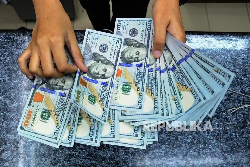 Pekerja sedang menghitung mata uang dolar di money change ilustrasi