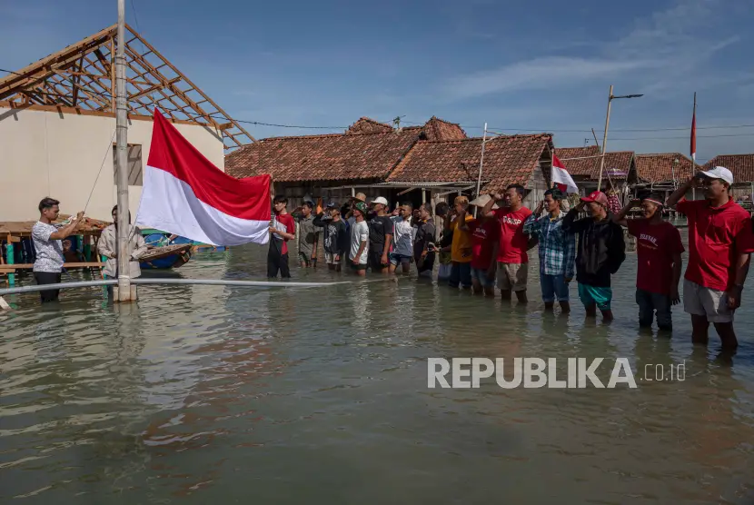 Warga membentangkan bendera merah putih di tengah banjir rob di Dusun Timbulsloko Kabupaten Demak Jawa Tengah BNPB sebut adanya banjir di musim kemarau sudah menjadi fenomena global