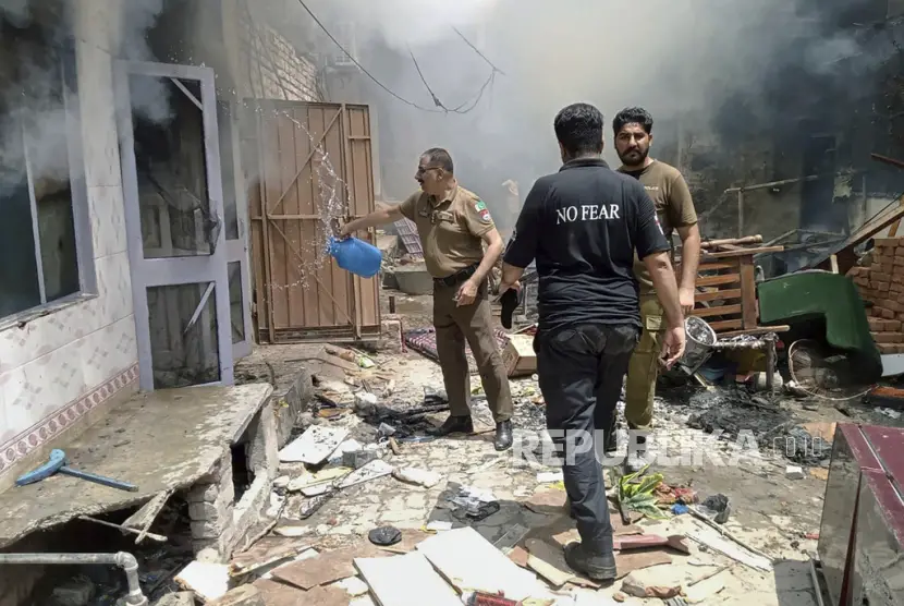 Polisi menyiramkan air ke rumah yang terbakar Jaranwala Pakistan Rabu 1682023
