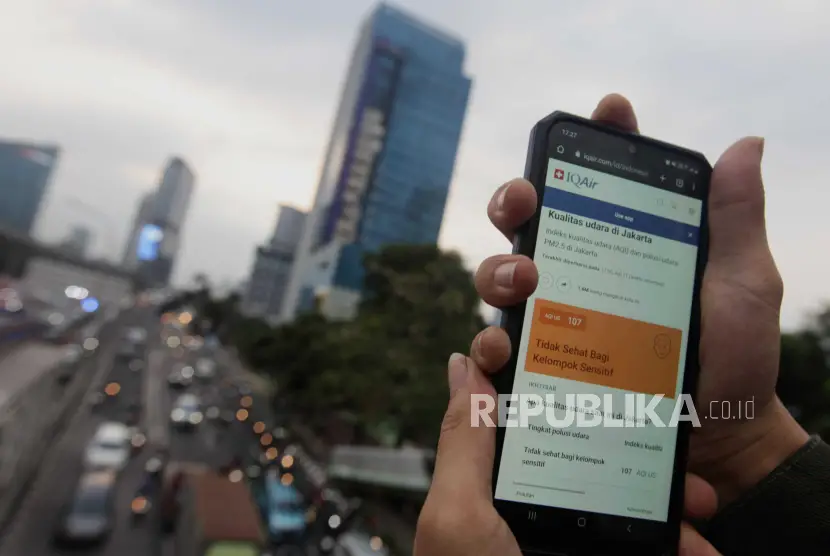 Warga memperlihatkan laman situs IQAir dengan latar belakang kendaraan terjebak kemacetan di Jalan Raya Gatot Subroto Jakarta DLH DKI Jakarta mengaku belum bisa menerapkan teknologi modifikasi cuaca