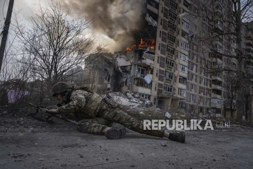 Seorang tentara Ukraina berlindung di depan gedung yang terbakar akibat serangan udara Rusia di Ukraina