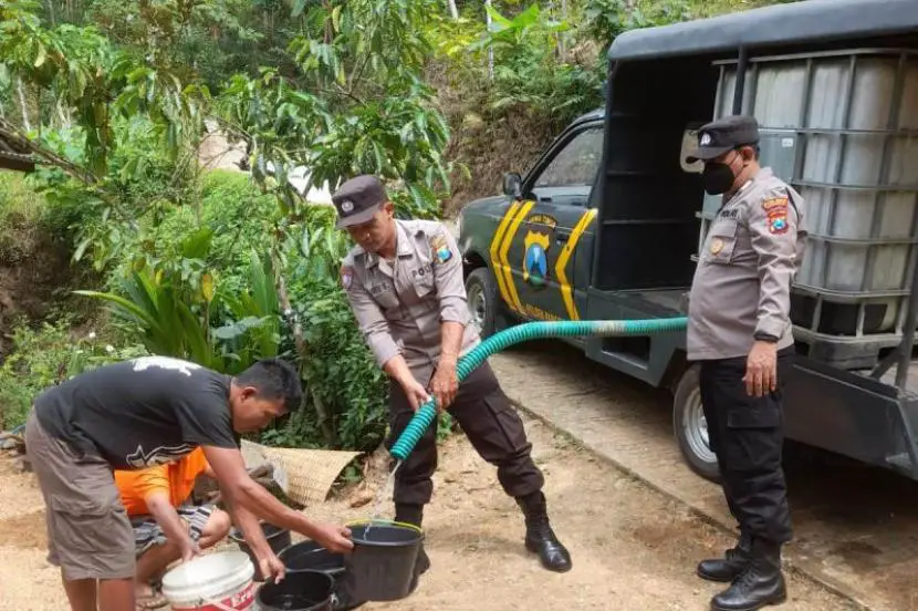 Polisi menyalurkan air bersih yang diusung menggunakan mobi patroli modifikasi tangki air