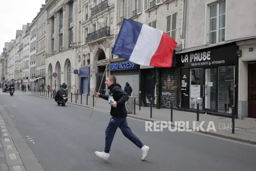 Seorang pria menyeberang jalan dengan bendera Prancis di tangannya ilustrasi