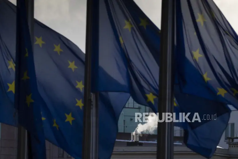 Asap mengepul dari cerobong asap di belakang bendera Uni Eropa yang berkibar tertiup angin di luar markas Uni Eropa di Brussel Kamis 24 Desember 2020