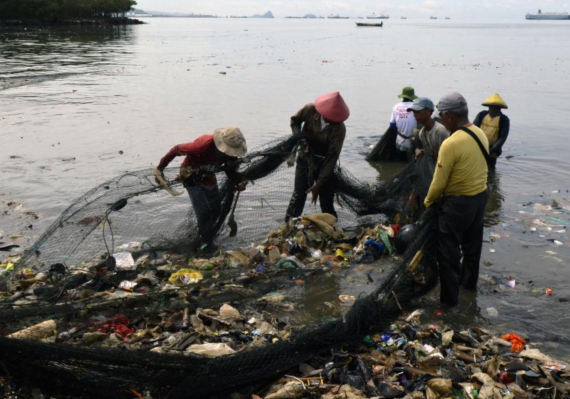 Nelayan membersihkan sampah yang tersangkut di jaring saat melaut di Pantai Sukaraja Bandar Lampung Lampung Selasa 25102022 Warga dan nelayan sekitar mengeluhkan limbah sampah rumah tangga yang terbawa arus sungai sampai ke pantai sehingga membuat hasil tangkapan para nelayan berkurang dan membuat lingkungan pantai menjadi kotor